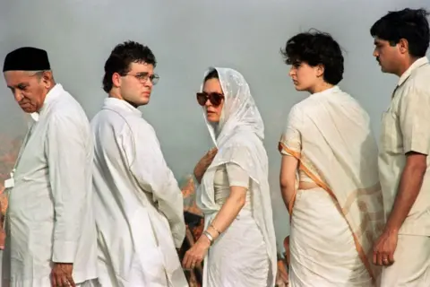 AFP via Getty Images Sonia Gandhi, the Italian-born widow of late Indian Premier Rajiv Gandhi, her daughter Priyanka (R) and son Rahul (2nd-L), turn to chanting mourners during the funeral of Rajiv at Shakti Sthal on the banks of the holy Yamuna River on 24 May 1991 in New Delhi