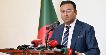 বাংলাদেশের পতাকার সামনে মাইক্রোফোনে কথা বলছেন পররাষ্ট্র প্রতিমন্ত্রী হুমায়ুন কবির